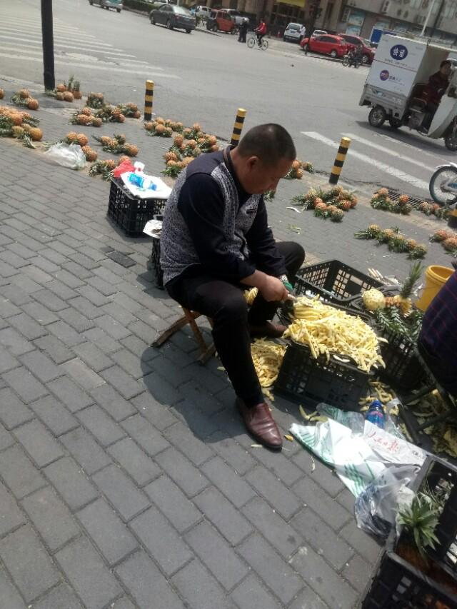 他在街头卖菠萝，200多个菠萝摆满一地。