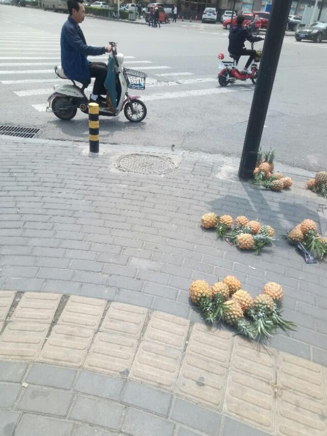 他在街头卖菠萝，200多个菠萝摆满一地。
